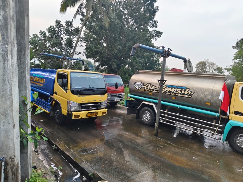 Dua truk tangki air bersih MFB, salah satunya tangki stainless bertuliskan Air Bersih, siap berangkat mengirim