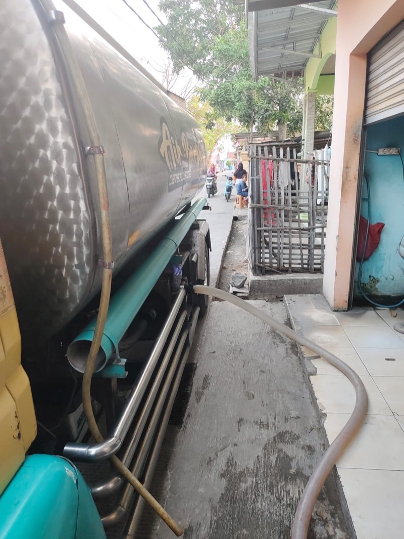 Selang dari tangki stainless MFB ditarik melewati gang menuju tandon usaha