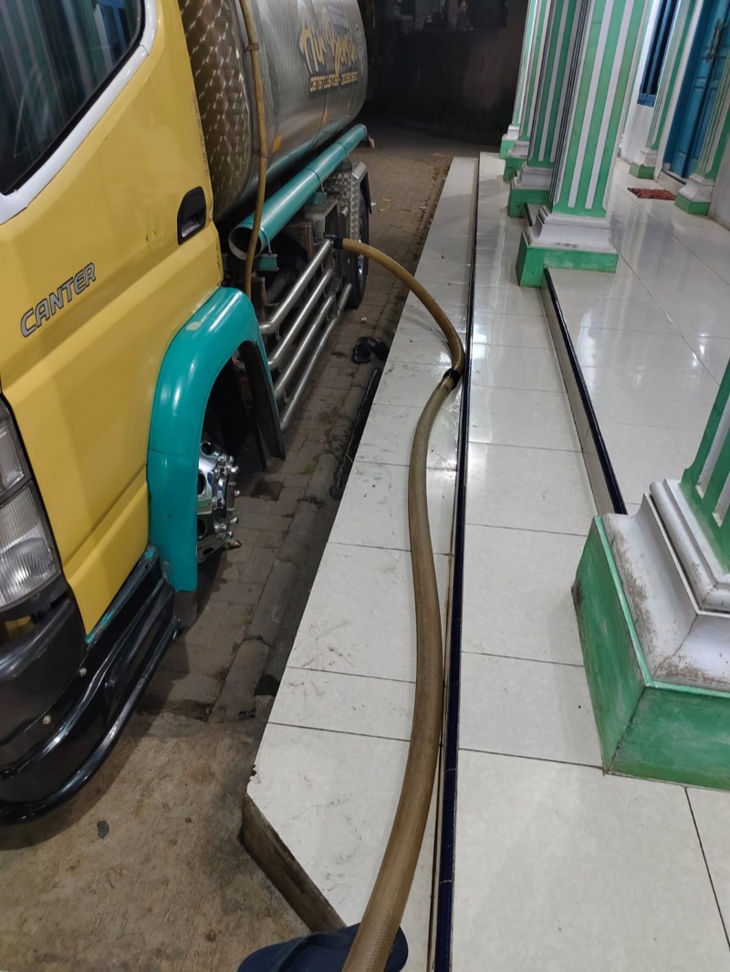 Selang dari truk tangki MFB ditarik masuk ke bangunan untuk mengisi tandon